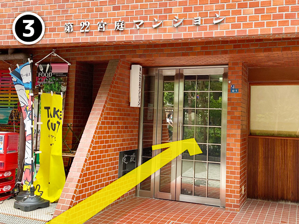 赤茶色のタイルと第22宮庭マンションの建物名がある入口
